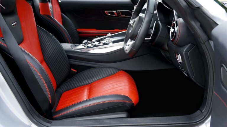 A car's interior displaying elegant red and black seats, highlighting the stylish seat covers that enhance the aesthetic.